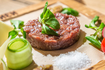 Tartare-a traditional appetizer of raw beef with spices lies on a wooden Board in the restaurant.