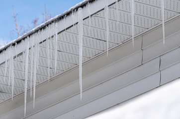 Icicicles hanging from a roofline in the sunlight