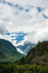 alpine landscape with lush forest, mountains and clouds