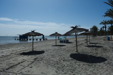 The beach at the beautiful resort of Lo Pagan, at the Mar Menor sea, in Spain.  Sun beds and spring sunshine by the calm waters of the Mediterranean. 