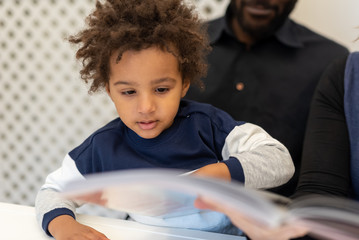 cute little mixed-race child flipping through a fairy tale book in his father's arms, details about...