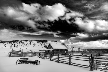 Rustic old corral in Black and white with winter snow and mountains