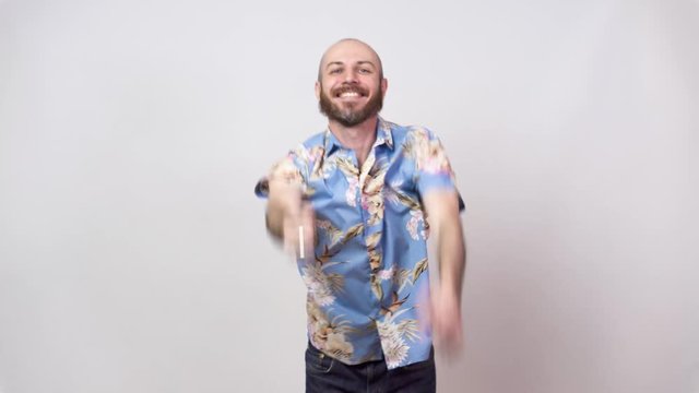 Funny dance of a man wearing hawaiian shirt. Cheerful bearded bald man dancing and having fun on white background.