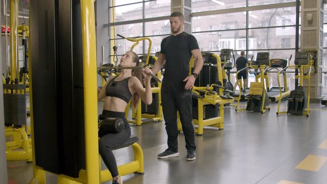 Young woman with instructor working out in gym