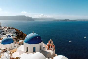 Fototapeta na wymiar Blue domed church in Oia overlooks the spectacular caldera surrounding the beautiful island of Santorini, Greece