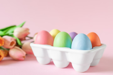 Easter holiday decorations on pink background with spring flowers, festive greeting card