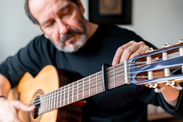 Seniors man are playing a guitar at home. Retired man learning playing a guitar.