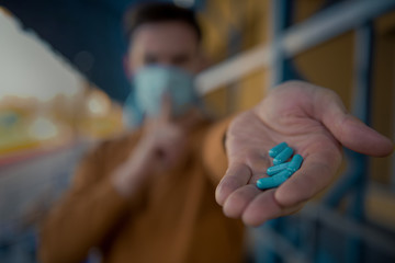 Men in surgical mask holding a bottle of medical pills against coronavirus in china, pharmacy...