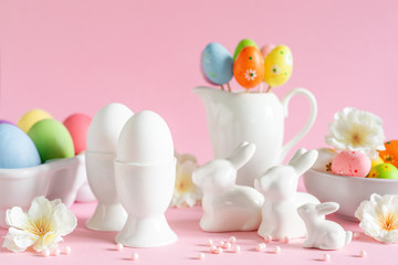 Easter holiday decorations on pink background with spring flowers, eggs and bunnies, festive greeting card