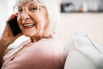 Cheerful old lady in glasses talking on cellphone