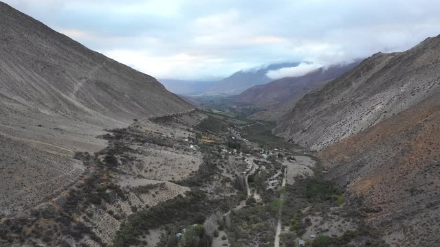An aerial view inside Andes mountains at Limari Valley, south Atacama. An amazing wild scenery. Arid idyllic valleys with green farm fields feed in by the river at the bottom of the valley
