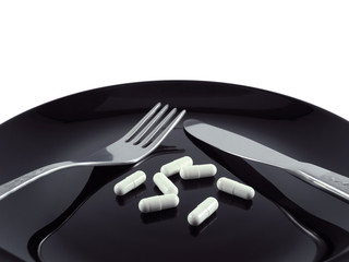 White pills capsules on black glossy plate with fork and knife on white background. Diet, anorexia, treatment concept.       