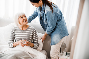 Loving granddaughter taking care of grandmother in bedroom