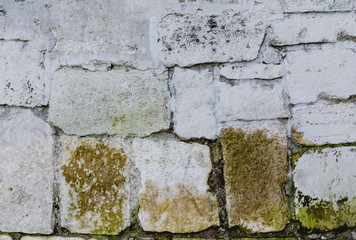 White stone wall with large bricks. An old ancient wall with an uneven surface, covered with moss from the Kremlin.Photo background.Texture of antiquity, rustic.