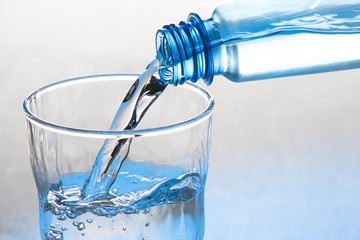 Water is pouring from a bottle into a glass Isolated on a white background