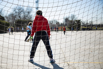 unrecognizable young boys and girls playing soccer in the schoolyard