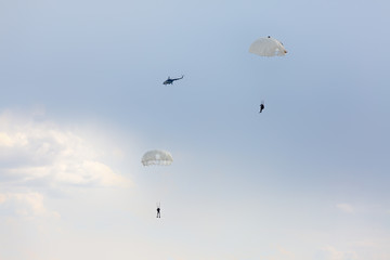 Paratroopers and a military helicopter in the sky
