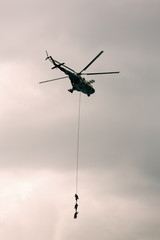Soldiers go down a rope from military helicopter.