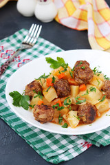 Stewed potatoes with meatballs on a white plate on dark background, Vertical orientation