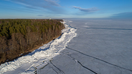 Sunlit frozen winter Gulf of Finland with some open water off the coast.