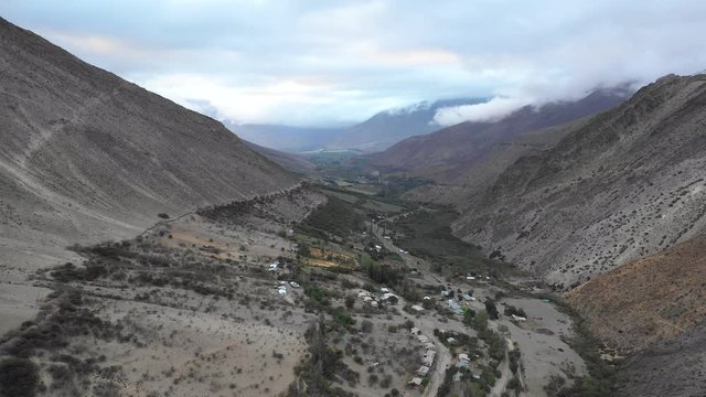 An aerial view inside Andes mountains at Limari Valley, south Atacama. An amazing wild scenery. Arid idyllic valleys with green farm fields feed in by the river at the bottom of the valley
