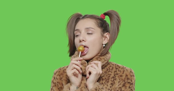 female model wearing leopard fur coat licking candy