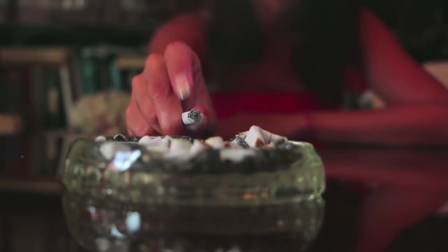 A woman shakes ashes in an ashtray. Shake off the cigarette ashes. Smoking a cigarette. Female hand ashing cigarette into ashtray