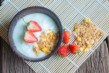 Top view of greek yogurt with strawberry, oats, and nuts for healthy breakfast.