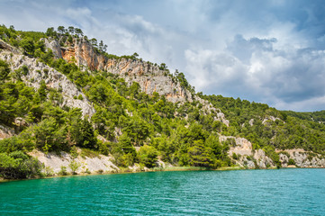 Fototapeta na wymiar Green hills with forest around Krka river with touristic boats in beautiful Krka National Park, Croatia