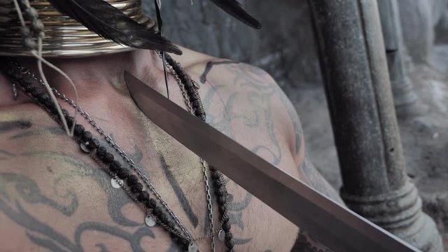 Adventure scene.Girl in a tomb raider style with sword near Tattooed masked skull ethnic pagan shaman at ancient temple 
