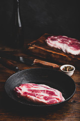 Raw pork neck steak in cast iron skillet