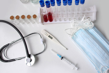 medical laboratory test tube with blood inside, stethoscope, syringe, protective masks, concept of...