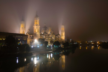Fototapeta na wymiar Cathedral of Our Lady of the Pillar illuminated on a foggy night