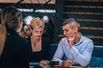 Group of young businesspeople brainstorming together in cafe and discussing new possible projects.