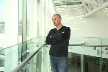 one man in a bright building of an airport lounge waiting at the window and looking at the street, travel concept