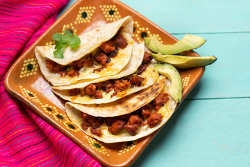 Mexican quesadillas with chorizo on turquoise background