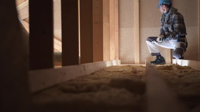 Construction Worker Surveys Attic To Determine Amount Of Work And Materials Needed To Finish Job. 