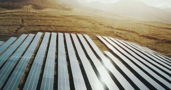 Flying over rows of blue solar panels at sunrise, solar farms are giving the future a chance with green renewable energy
