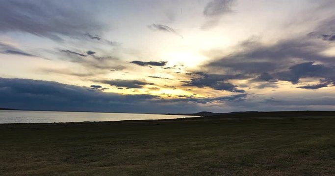 Sunset over a human made lake at Mongolia close by the village of bulgan. Time lapse in the Mongolian steppe. horizon view over the lake with fast moving clouds