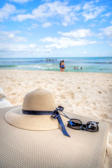 Vacation theme with sunglasses and hat in a tropical beach background