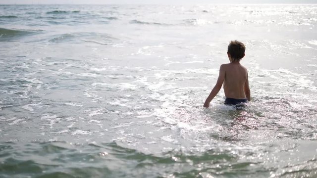 Child with back running in sea water