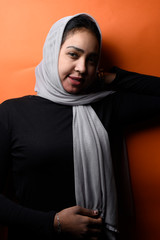 Portrait of happy Arabic girl wearing Hijab on orange background,beautiful Middle Eastern girl in Arabic Traditional Abbaya 