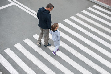 A man and a small child on a zebra crossing trespassing by crossing the street. In the summer on...