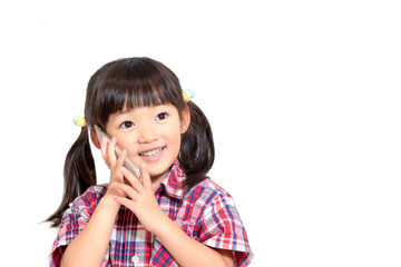 笑顔でスマートフォンで話をする幼い女の子。スマートフォン、連絡、伝言、電話イメージ