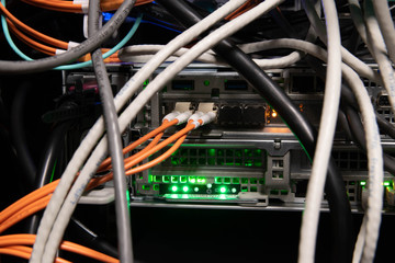 two orange optic fiber cables connected to a server with green lights