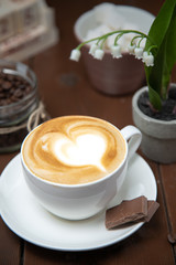 cup of coffee with cream on wooden background