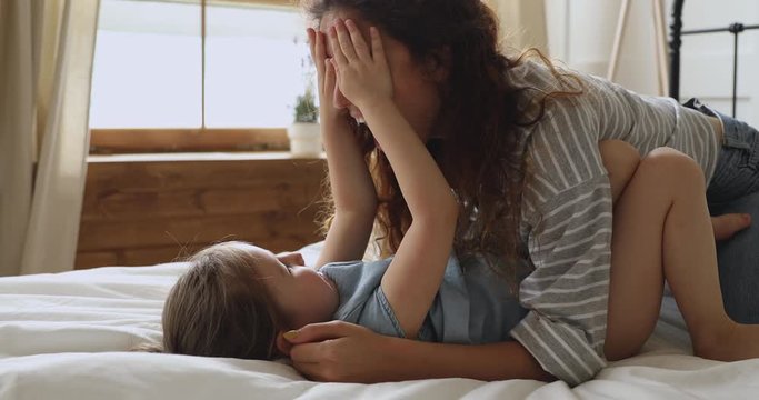 Young Mother Playing Peek A Boo Game With Preschool Daughter.