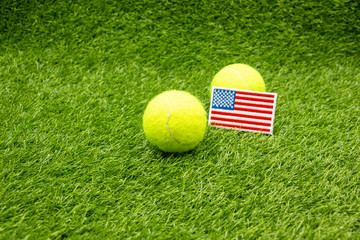 Tennis ball with flag of America on green grass