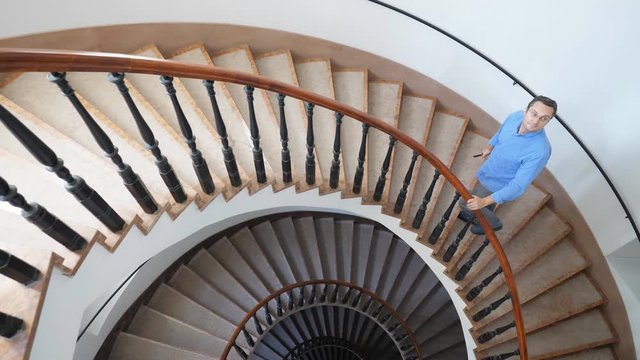 Man climbing spiral stairs takes photo of stylish architecture