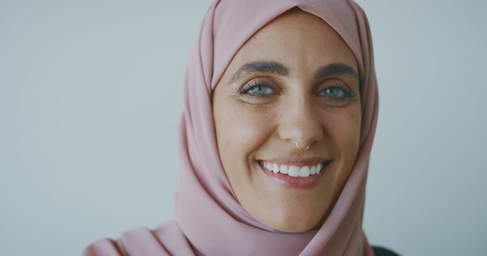 Portrait Of A Young Progressive Muslim Woman Wearing A Nose Ring And A Pink Traditional Hijab Head Scarf, Smiling Into The Camera Laughing With Green Eyes